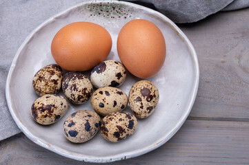 Fresh small spotted partridge or quail bird and brown chicken eggs