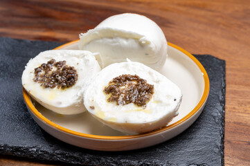 White balls of Italian soft cheese Mozzarella di Bufala Campana stuffed with black truffles mushrooms