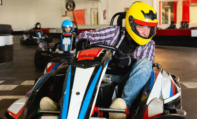 Portrait of lucky man driving racing car at kart circuit