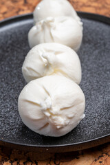 Eating of fresh handmade soft Italian cheese from Puglia, white balls of burrata or burratina cheese made from mozzarella and cream filling