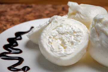 Eating of fresh handmade soft Italian cheese from Puglia, white balls of burrata or burratina cheese made from mozzarella and cream filling served with balsamico cream