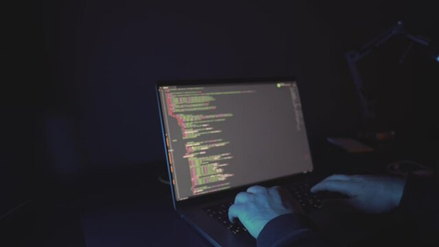 hacker: hacker who writes code. man working on laptop in night light