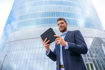 Portrait of a young male businessman or entrepreneur outside the office, with a tablet in his hand