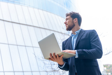 Young businessman with a computer in a glass building, finance concept