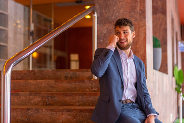 Businessman or finance man teleworking with the phone at the entrance of a hotel at an event