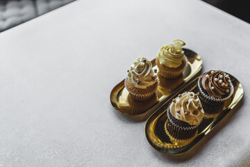 Carefully made cupcakes with stable frosting and edible pearls standing on golden plates. Copy space. High quality photo