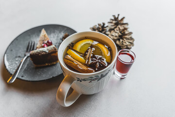 Christmas winter tea with cinnamon, aniseed and orange slices serves with cake and liquor. Gray table. Copy space. High quality photo