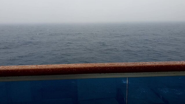 Sea, agitated, being filmed from the cabin of a cruise ship on a rainy day.
