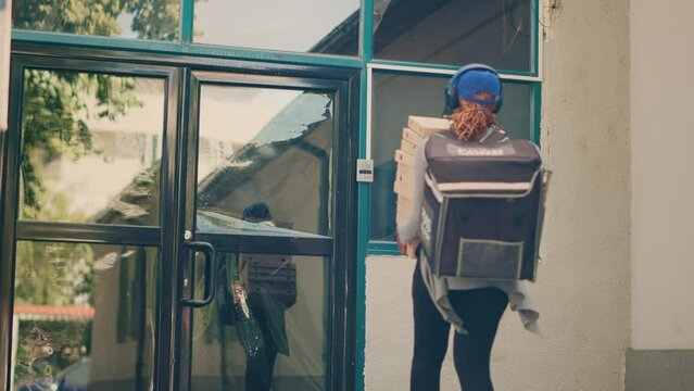 Female Delivery Worker Carrying Pile Of Pizza Boxes To Deliver Restaurant Order To Customer, Food Delivery Service. Client On Phone Call Taking Meal Packages From Pizzeria Courier. Handheld Shot.