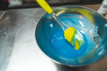Blue icing in a stainless steel bowl with spatula. Cookery and bakery concept. High angle view. High quality photo