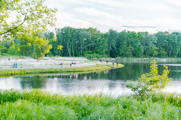 City's public lake with green grass and trees around. Walking. Sky. Summer. Bright. Holiday. Spring. Meadow. Lawn. Human. Peaceful. Recreation. Peace. Walking. Sunlight. Tropical