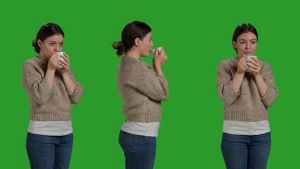 Close up of casual adult enjoying coffee drink on greenscreen backdrop, drinking caffeine beverage in studio. Relaxed optimistic woman holding cup of refreshment on camera, leisure activity.