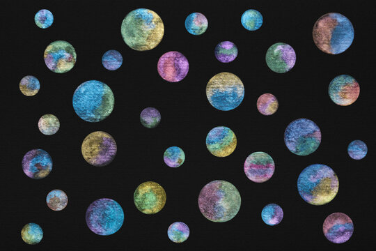 Planets painted with shining watercolor paints on black watercolor paper. Bright watercolor circles with a metallic sheen on a black background. Outer space with glowing planets.