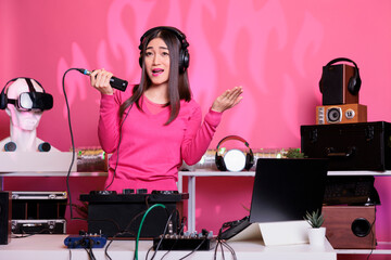 Smiling performer standing at dj table playing techno music at professional turntables in studio...