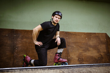 Young roller skater in helmet posing and looking at camera on ramp 