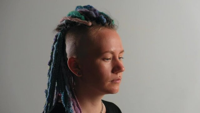 a model girl with dreadlocks and a tattoo is sitting in a white studio against the background of studio light. Gay girl. Concept of gender expression, identity and diversity. gender person. Feminism