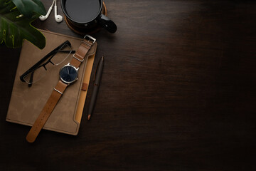 Wooden desk with  wrist watch, notebook, eyeglasses and coffee cup. Top view with copy space for your text.