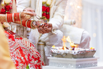 Fototapeta na wymiar Indian Hindu wedding ceremony pooja ritual sacred fire and hands close up