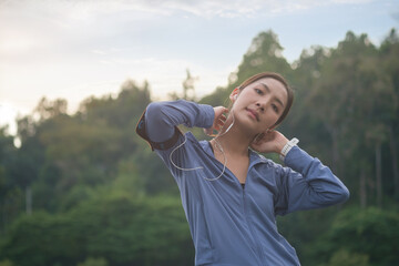 Portrait of sportswoman listening to music with earphone, taking break during jogging outdoors.
