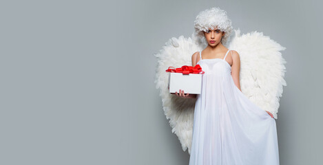 Valentines day banner with sexy angel woman. Angel woman with feather white wings and gift. Beautiful woman posing with angel wings.