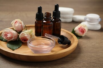 Rose essential oil and flowers on wooden table