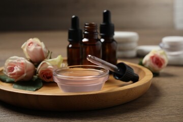 Fototapeta na wymiar Rose essential oil and flowers on wooden table