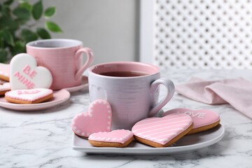 Delicious heart shaped cookies and cup of tea on white marble table