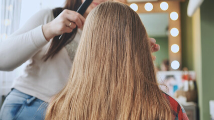 The makeup artist prepares the girl's hair for the hairstyle.