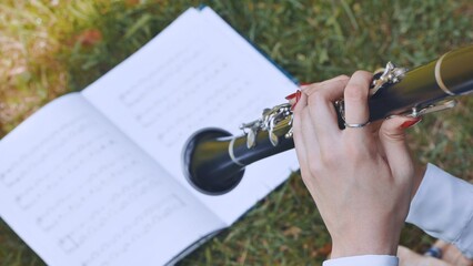 The girl plays the clarinet by notes.