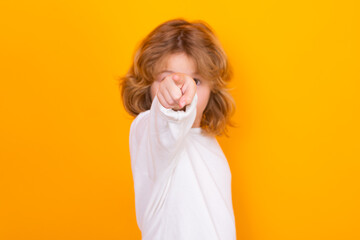 Surprised child pointing at you on yellow isolated studio background. Shocked kid pointing to copyspace, showing promo offers, points away.