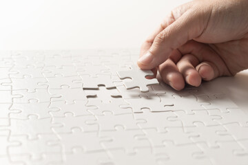 Hand completing white puzzle