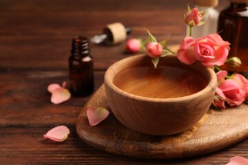 Obraz na płótnie Canvas Bowl of essential oil and beautiful roses on wooden table. Aromatherapy treatment