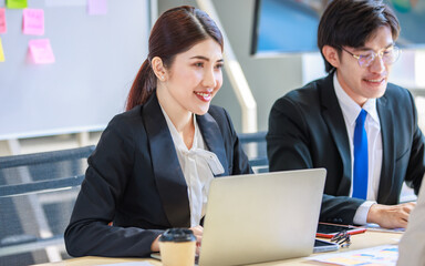 Closeup shot of Millennial Asian young professional successful female businesswoman employee in formal suit sitting discussing brainstorming talking with male female colleagues in meeting room