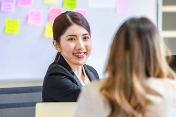 Millennial Asian young professional successful male female businessmen businesswomen in formal suit sitting smiling discussing holding hands showing unity together in company office working desk