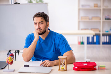 Young male doctor cardiologist in time management concept