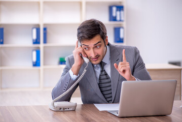 Fototapeta premium Young male employee unhappy with excessive work in the office