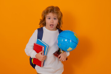 School and education kids concept. Clever school boy with school supplies on yellow studio background.