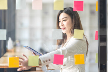 Business female employee with many conflicting priorities arranging sticky notes commenting and...