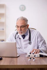 Old male doctor working in the clinic