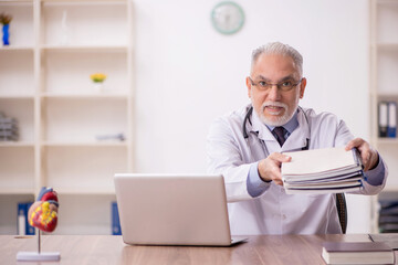 Old male doctor working in the clinic