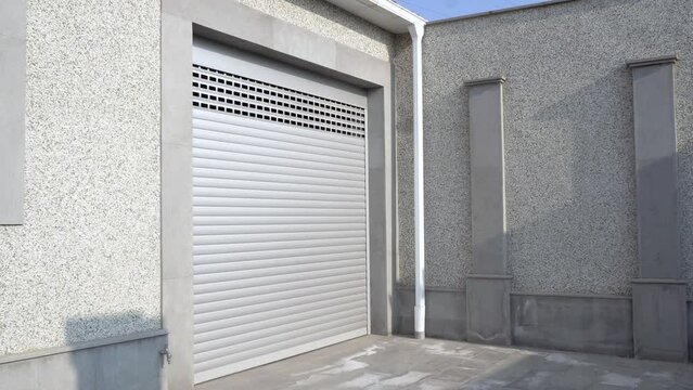 Human hand opening roller shutter gate. Metal roller garage door as background. Automatic electric roll-up garage gate. Garage with rolling gates.