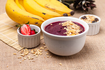 Acai bowl on the table with bananas, strawberries and granola.