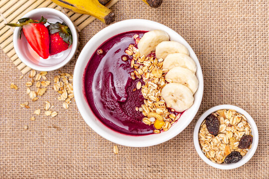 Acai bowl on the table with bananas, strawberries and granola, top view.