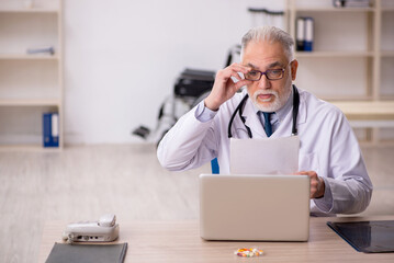 Old male doctor working in the clinic