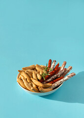 Sticks of Chorizo, mini fuet and picos bread sticks in bowl on the light blue background with hard...