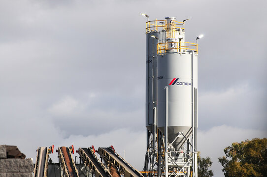 CEMEX cement storage silos and conveyor equipment at an industrial materials plant, illustrating large-scale aggregate handling and construction supply operations