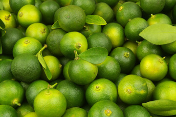 Green limes with fresh leaves as background or texture