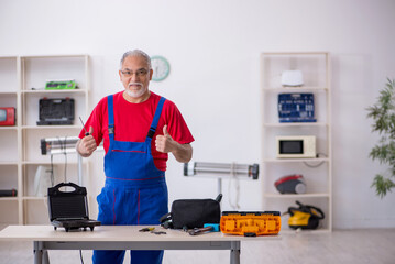 Old repairman repairing sandwich maker at workshop