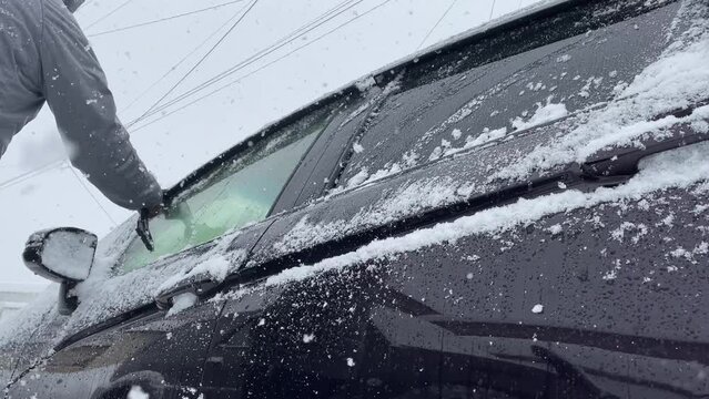 車に積もった雪をよせている　冬　運転　イメージ