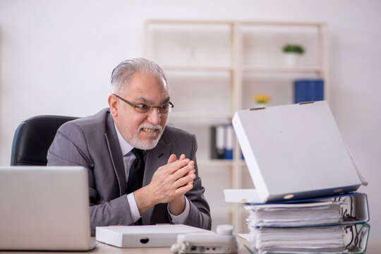 Old male employee eating pizza in the office - Powered by Adobe